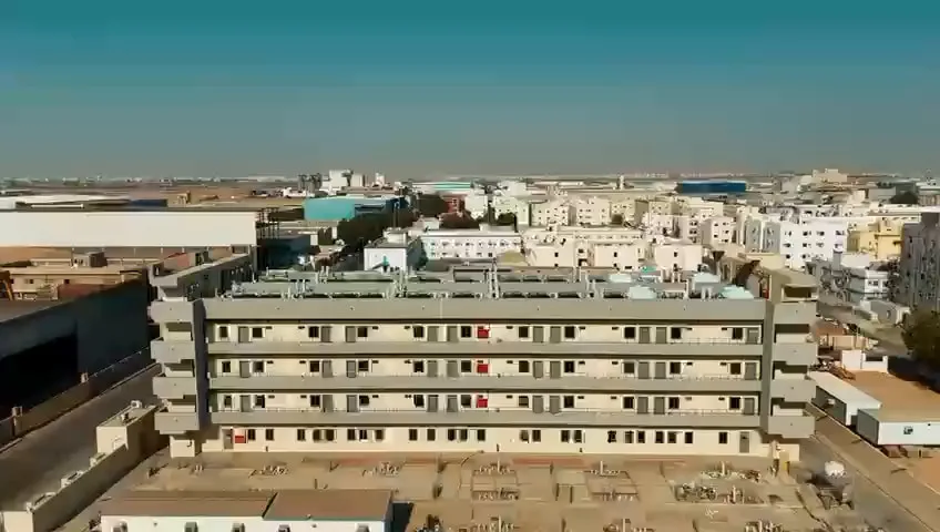 منظر جوي لمبنى سكن العاملين ووحدات التكييف على سطحه، وخلفه أحياء المدينة
